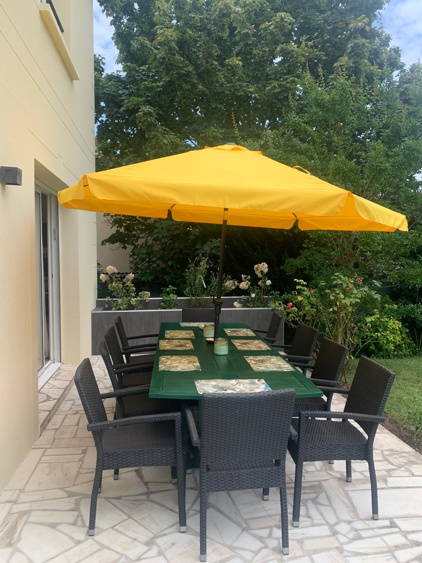 Terrasse du F3 rez-de-jardin avec grande table extérieure et parasol jaune